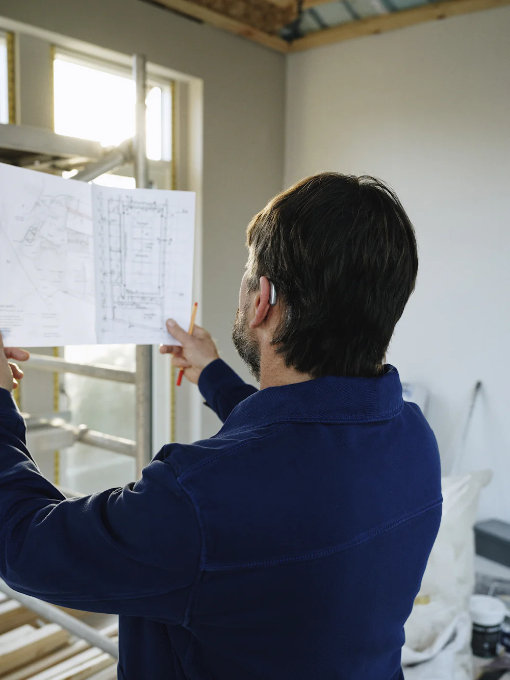 A builder checking structural drawings on site
